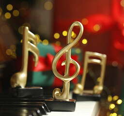 Christmas atmosphere. Golden treble clef on piano against blurred lights, closeup. Bokeh effect