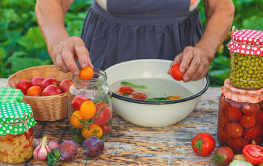 Senior woman preserving vegetables in jars. Selective focus.