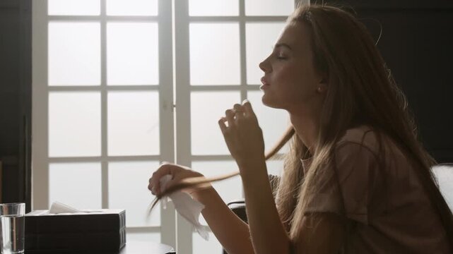 Side shot of anxious Caucasian young woman fidgeting hair and tissue while visiting psychologists office