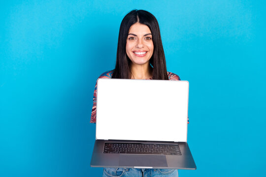 Happy young woman with laptop on blue background smiling at camera promoting online shopping and modern style