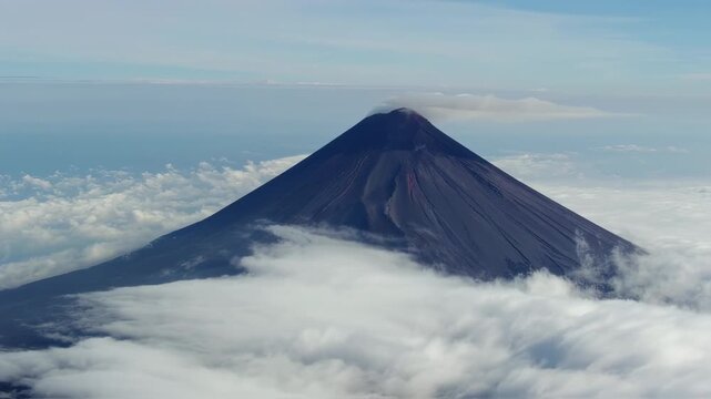 A dark, cone-shaped mountain emerges from clouds, with a visible volcanic vent