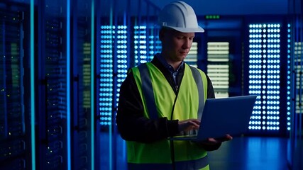 Data center worker checks laptop computer in server room with blue lights - Powered by Adobe