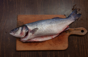 Gutted, ready to cook lavraky fish on a wooden cutting board