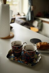 Cozy morning scene with tea cups and a croissant in a kitchen setting for breakfast 