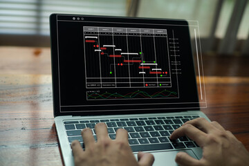 Hands typing on a laptop displaying a project management timeline and Gantt chart, representing productivity, workflow planning, task tracking, and digital project management.