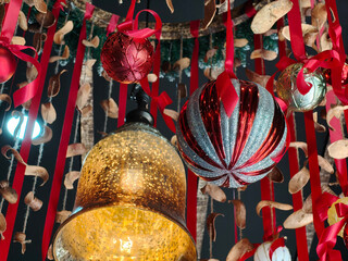 Colorful round ornament adorned with a red bow hangs in the ceiling, perfect for Christmas decoration. Background