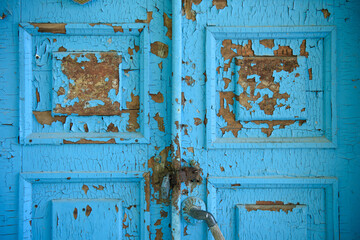 Weathered blue wooden door with peeling paint and rusted latch
