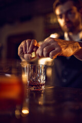 Bartender squeezing citrus peel over glass during cocktail preparation. Concept of mixology finesse, aromatic drink finishing, crafted spirits, and elevated beverage rituals.
