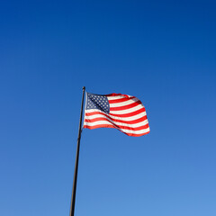 Square image of nAmerican flag, also called Stars and Stripes, Old Glory or Star-Spangled Banner flying in  blue sky in Maine, USA, symbol for freedom and patriotism, 4th of July