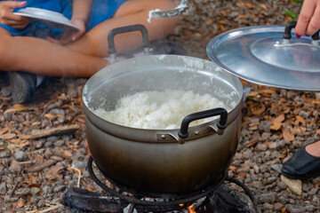 The cooking of jasmine rice over a wood-fired stove by Junior Red Cross students during an outdoor camp.