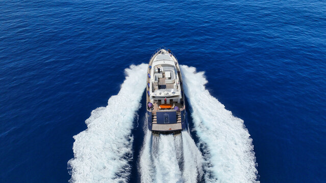 Aerial drone photo of small luxury yacht cruising in deep blue sea near Aegean island, Greece