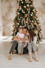 New Year, family, mom and dad with a child hugging each other near the Christmas tree, celebrating the holiday, waiting for the holiday, family New Year photo