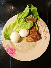 Healthy meal, fried fish with boiled eggs and lettuces.