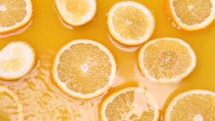 Bright orange slices float gently in fresh orange juice as ripples form from a soft pour. A refreshing, vibrant citrus scene with smooth liquid motion and sunny color tones. - Powered by Adobe