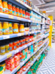 Blur supermarket background. Defocused shelves with products. Grocery store. Retail industry. Inflation concept. Aisle. Consumer packaged goods. CPG. Rack. Tariff. Price hikes. Jars of canned food.