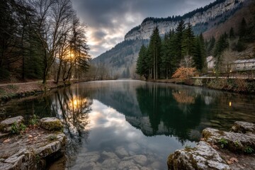 Fototapeta premium A serene lake reflects surrounding mountains and trees under a dramatic sky, creating a peaceful nature scene.