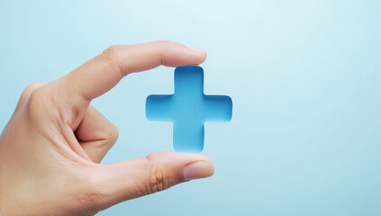 A hand holding a blue medical cross symbol, representing healthcare and wellness on a blue background.