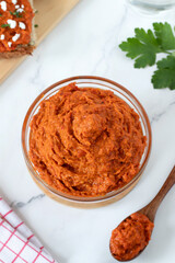 Homemade ajvar (red pepper dip) in a bowl on white kitchen table. Top view. Traditional macedonian food concept.