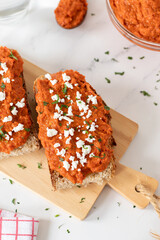 Ajvar (roasted red pepper dip) on bread slices with cheese and parsley. Top view. Traditional Macedonian food concept.