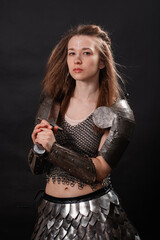 Obraz premium Portrait of a young woman, fantasy warrior in armor with a sword in her hands isolated on a dark background.