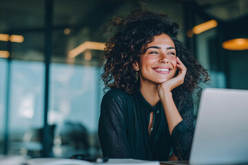 Businesswoman smiling while working on her laptop in a modern office.