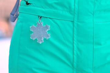 Close up of snowflake reflector on turquoise winter clothing for safety in the dark