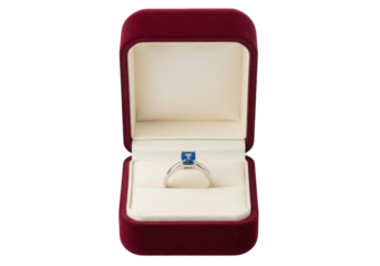 Isolated engagement ring with blue sapphire gem stone in an open, red velvet ring box