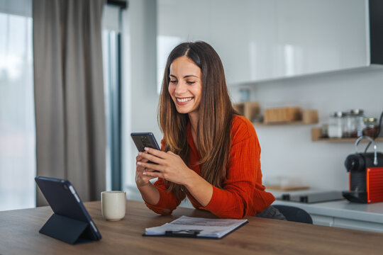 Happy woman using smart phone working from home office