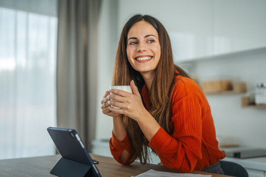 Woman drinking coffee using tablet for video call