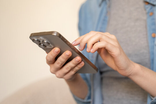 Woman's hands holding and using smartphone, swiping, scrolling, surfing in social media, reading text message, chatting with friend, browsing on internet. Female shopping online at home. Close up