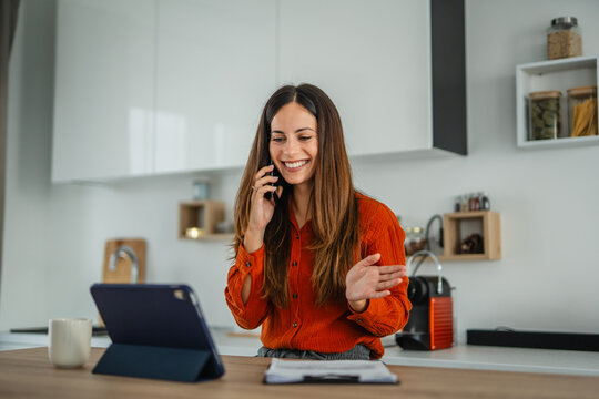 Woman multitasking working from home in modern kitchen