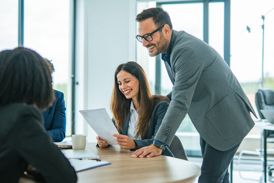 Business colleagues smiling discussing documents during office meeting