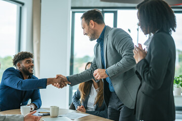 Businessmen shaking hands making deal at office meeting