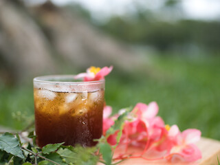 Making iced Americano coffee with fresh palm fruit on a wooden floor surrounded by flowers, relaxing in the park.