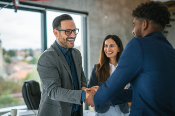 Business people shaking hands celebrating partnership deal in office