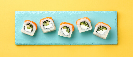 Philadelphia sushi roll with salmon and avocado on a light blue background in sunlight, evoking fresh fusion sushi.