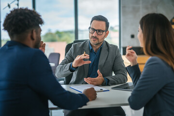 Financial adviser discussing contract with diverse couple in office meeting