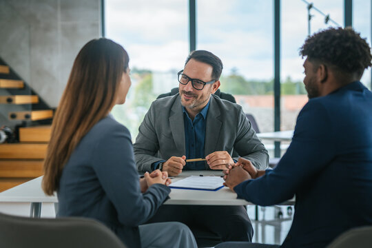 Financial adviser discussing contract with diverse couple in office meeting