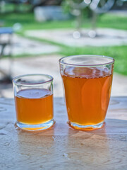 Wild honey in bottles and clear glasses on a wet wooden background