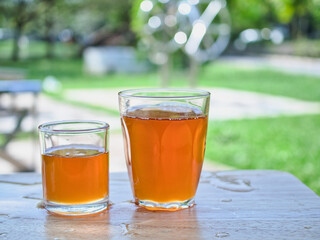 Wild honey in bottles and clear glasses on a wet wooden background
