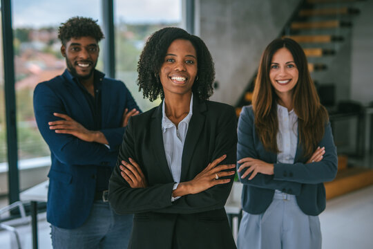 Diverse business team smiling with arms crossed in modern office