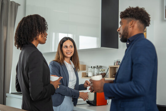 Diverse colleagues discussing business during a coffee break in office kitchen