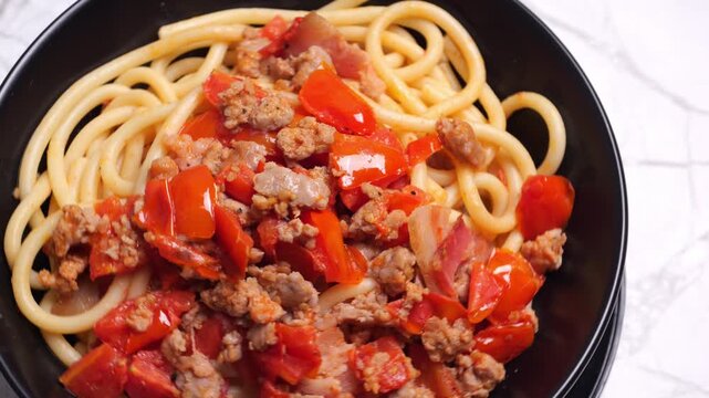 Piatto di pasta condita con salsiccia e pomodorini, piatto che gira