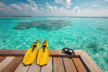 Turquoise ocean vista, yellow flippers and diving mask rest on a wooden dock under a blue sky
