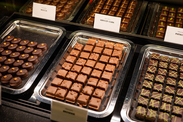Variety of handcrafted truffles and pralines in a window shop display. Close up, no people