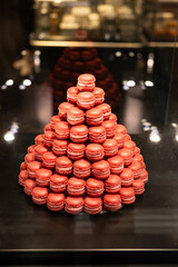 A pyramid of dark pink macarons inside a shop window display. Close up shot, no people