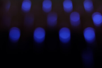 Abstract blurred background featuring a grid of glowing blue bokeh dots against a deep black setting. The out-of-focus LED lights create a geometric pattern suggesting technology, nightlife