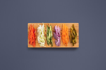Brightly colored vegetables are neatly arranged on a wooden cutting board.