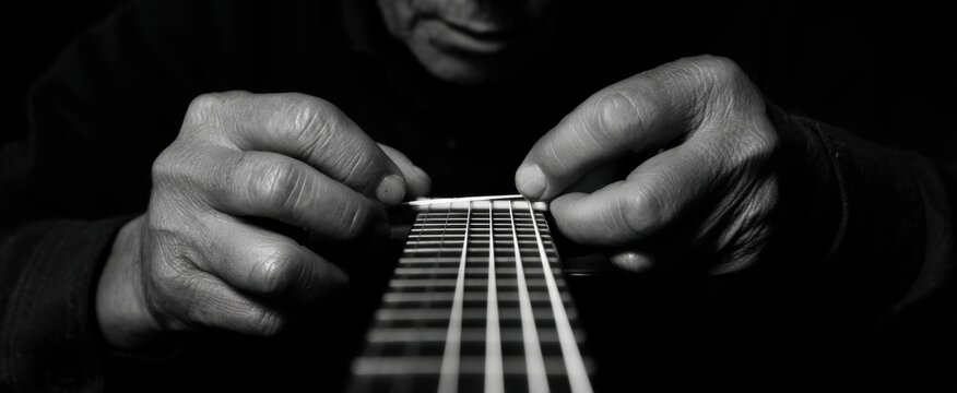 the skilled man deftly replacing a damaged guitar string by hand