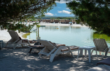 White deck chairs by the lake in the shade between coniferous trees